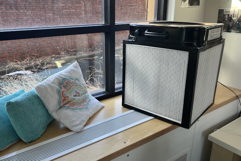 a cube about 2 feet on the side sits on a window ledge by a large window