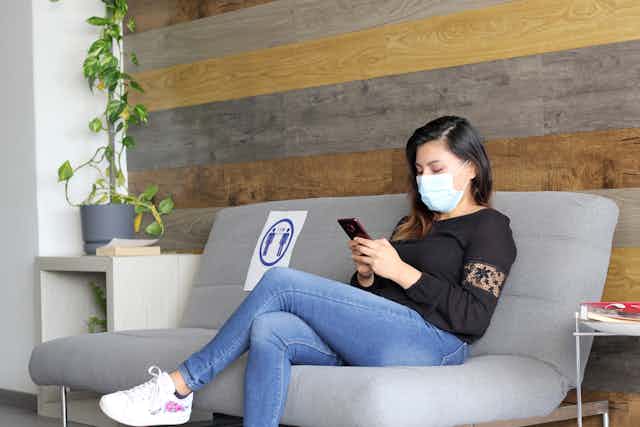 Woman in mask sits in a waiting room