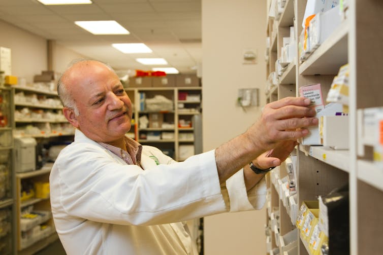 Pharmacist takes medicine from a cupboard.