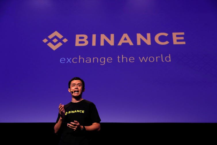 Changpeng Zhao talking on stage with Binance logo behind him