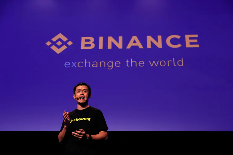 Changpeng Zhao talking on stage with Binance logo behind him