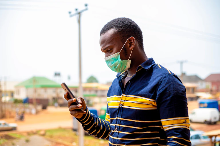 Man wearing mask uses cellphone