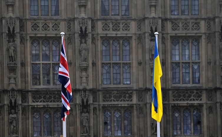 A union flag and a Ukranian flag flying in front of the Houses of Parliament in Westminster.