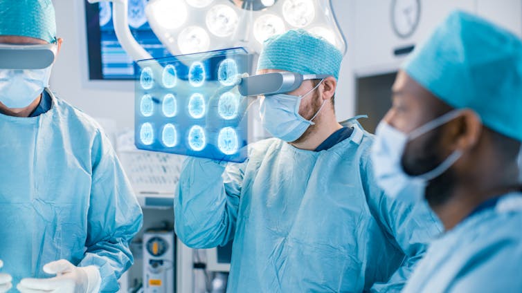 surgeons in scrubs looking at a holographic screen showing brain scans