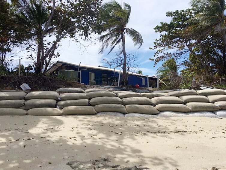 A metre-high wall of sandbags divides the space between beach and a home in the Torres Strait.