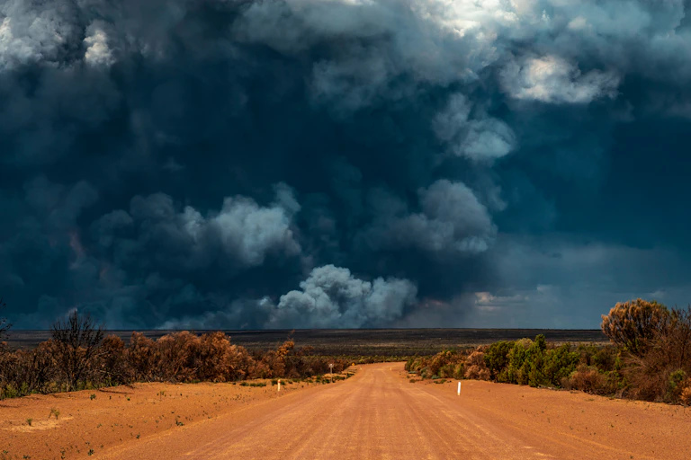 large wildfire smoke over dusty road