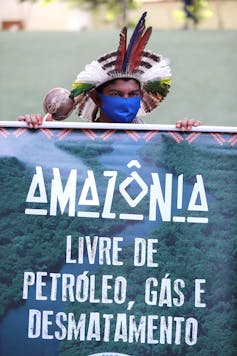Man in traditional hat holds protest sign