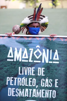 Man in traditional hat holds protest sign