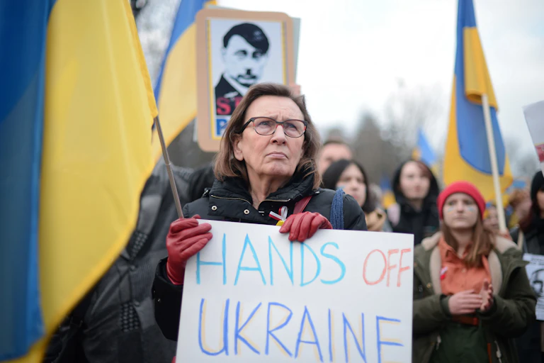 Anti-war protesters, one with a signs saying 'Hands of Ukraine' another poster likens Vladimir Putin to Hitler.Putin