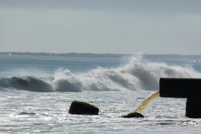 A sewage outflow pouring liquid into the sea.
