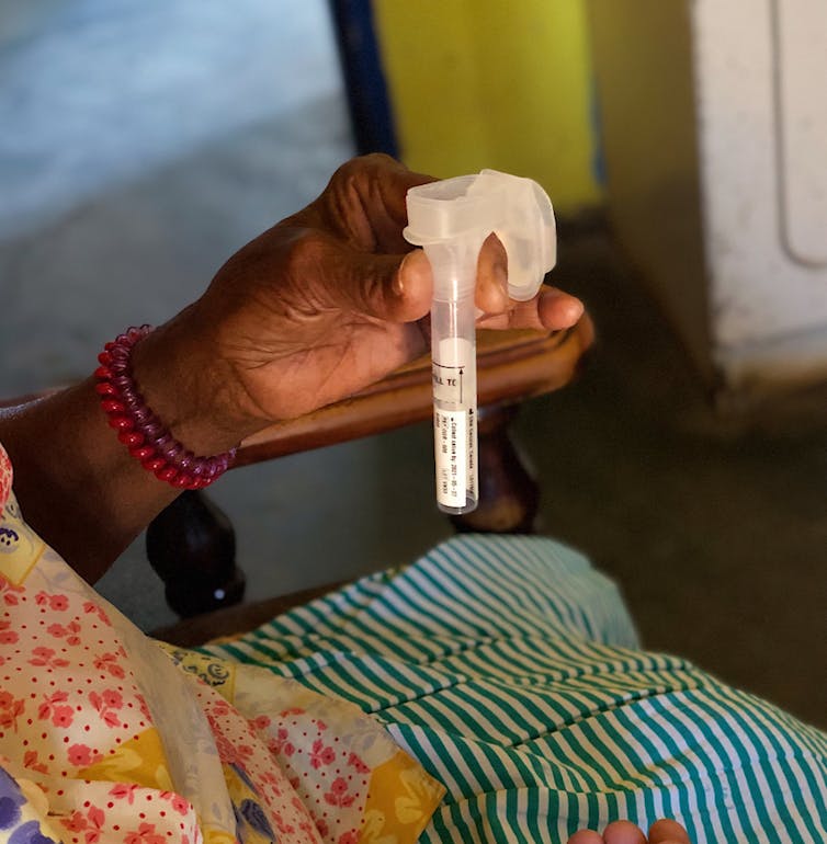 Enrolled research participant holding the spitkit during saliva collection