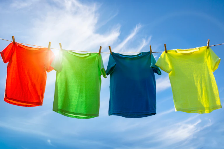 Coloured t-shirts hanging on line in sun