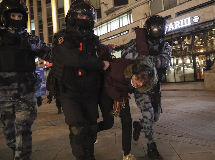 A protestor is forcibly taken into custody by Russian police, Moscow February 2022.