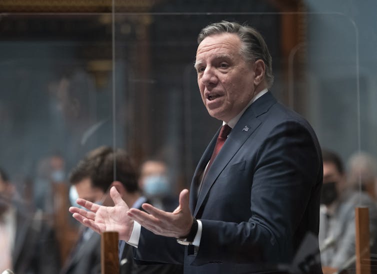 Man in a suit with a red tie gesticulating with his hands