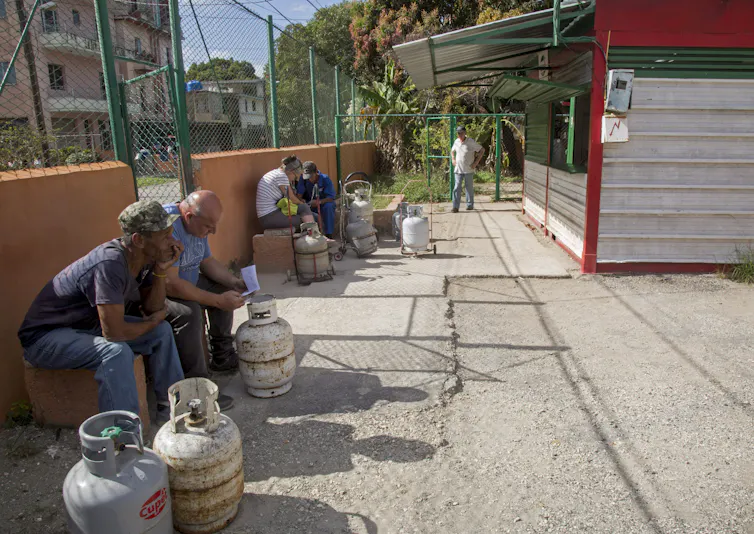 Men sit in the sun with empty fuel tanks.