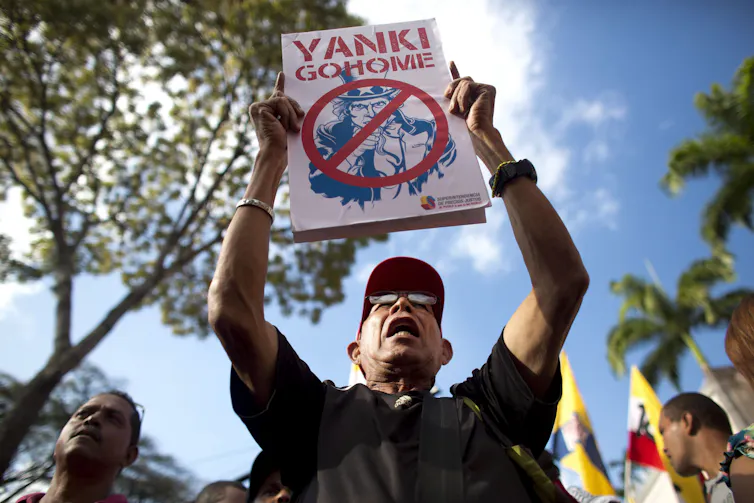 A man in a baseball cap holds up a sign that says Yankee Go Home.