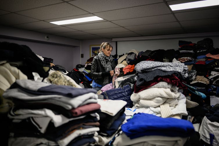 A volunteer tends to piles of donated clothing.