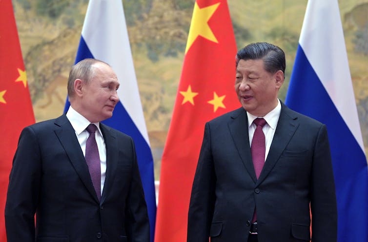 President Putin and President Xi Jinping in front of flags.
