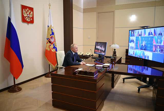 Russian president Vladimir Putin sites behind his desk talking with members of Russia's Security Council via video link.