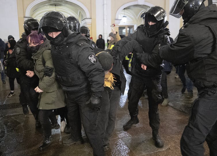Russian policemen wearing riot gear detaining protesters at a rally in St Petersburg, March 2022.