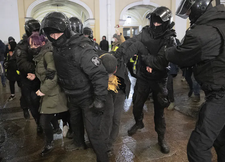 Russian policemen wearing riot gear detaining protesters at a rally in St Petersburg, March 2022.