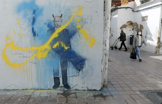 Graffiti image of Putin daubed with yellow and blue paint. 