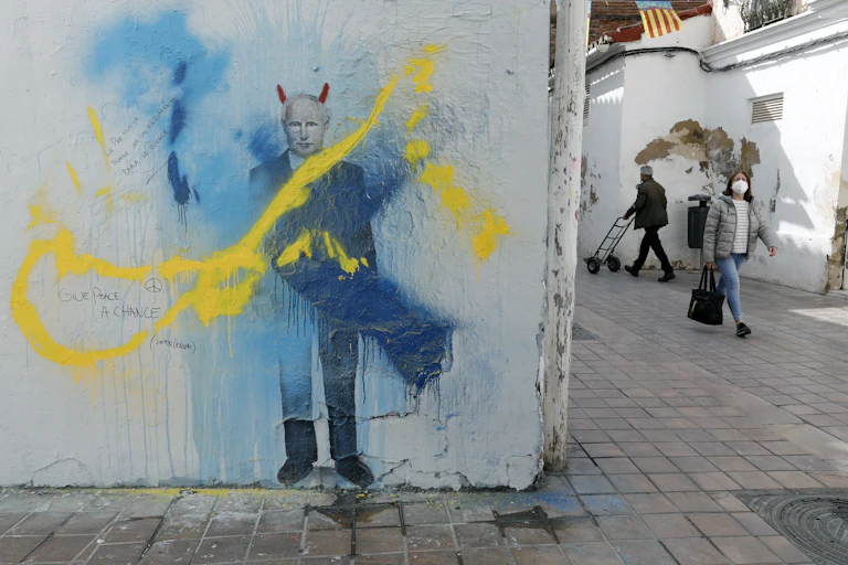 Graffiti image of Putin daubed with yellow and blue paint.