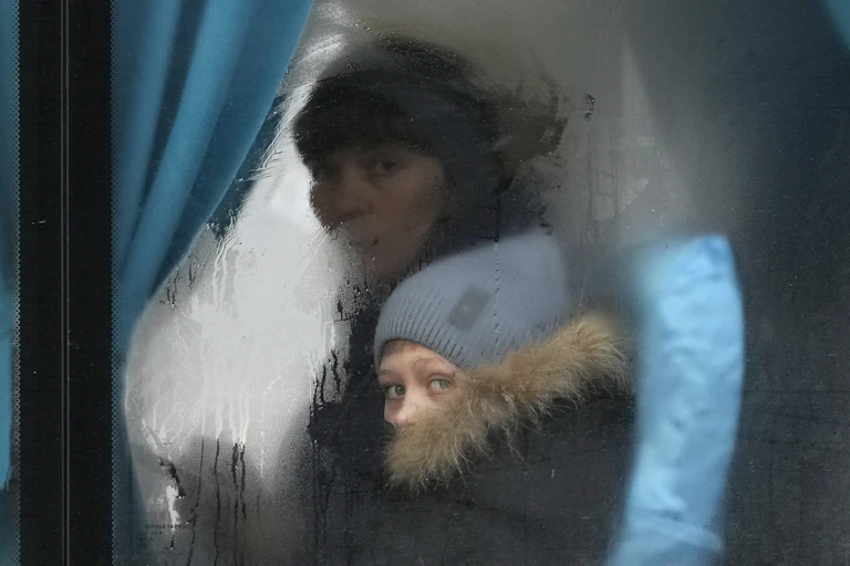 Une femme et un enfant regardent à travers la vitre embuée d'un bus.
