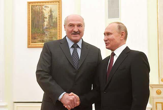 The presidents of Belarus and Russia shake hands, wearing black suits.
