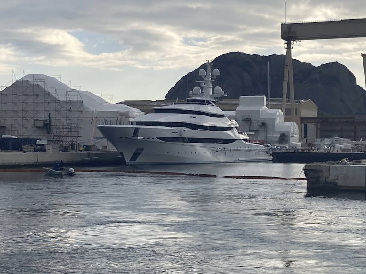 A large yacht sits in the water at a dock