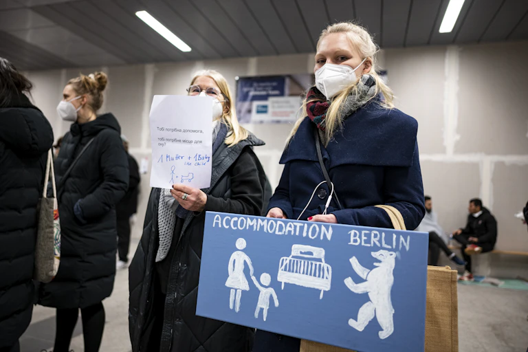 Women hold signs offering a place to stay