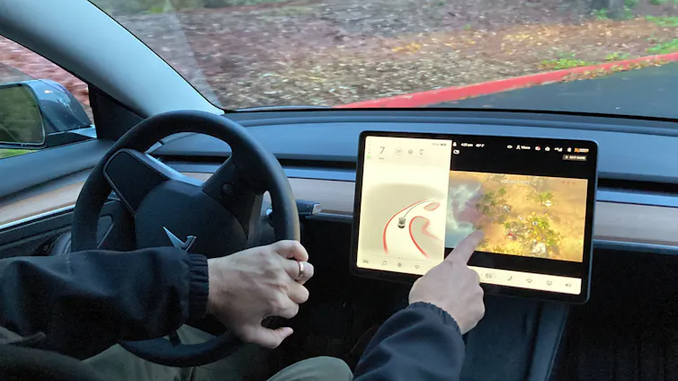 A person playing video games on a touch screen while sitting in the driver's seat