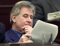 A grey-haired man reads a document.