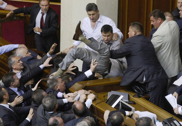 Men in suits attack one another.
