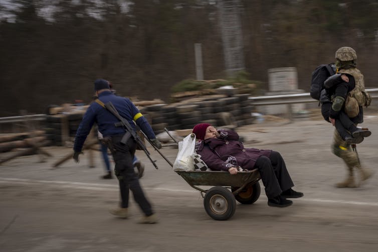 A Ukrainian soldier and a militia man help a fleeing family.