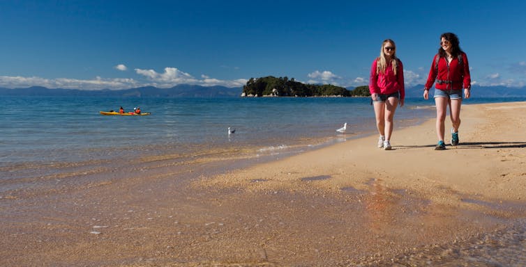 Two teenagers walking along a beach.