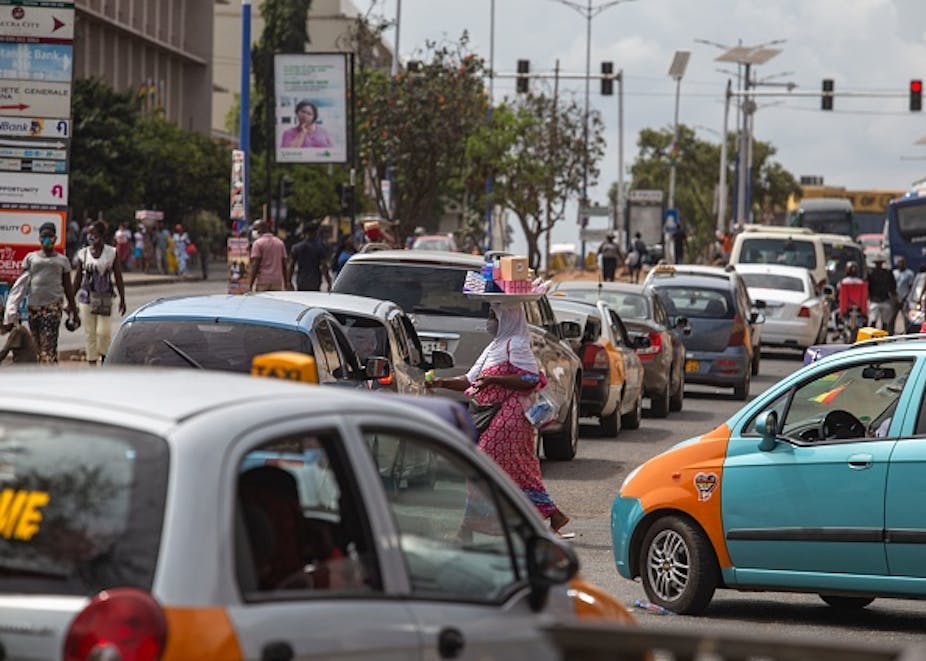 People walk through traffic in Accra