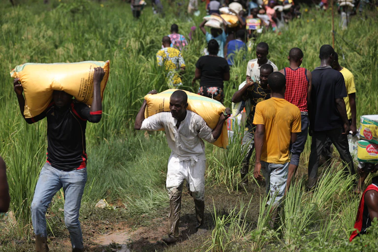 People carrying bags of food on thier heads and shoulder