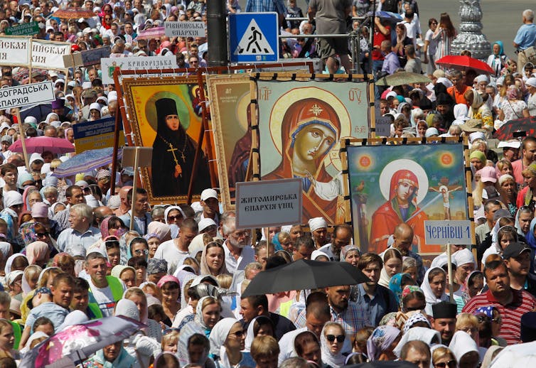 A crowd carries religious posters and banners.