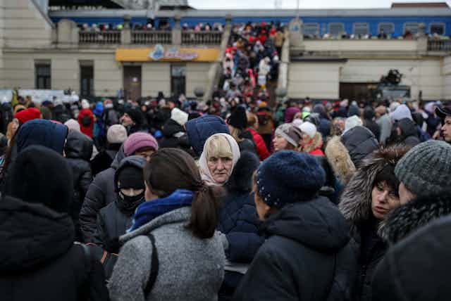 A large crowd of people gathering at a train station in Ukraine, try to board trains. 