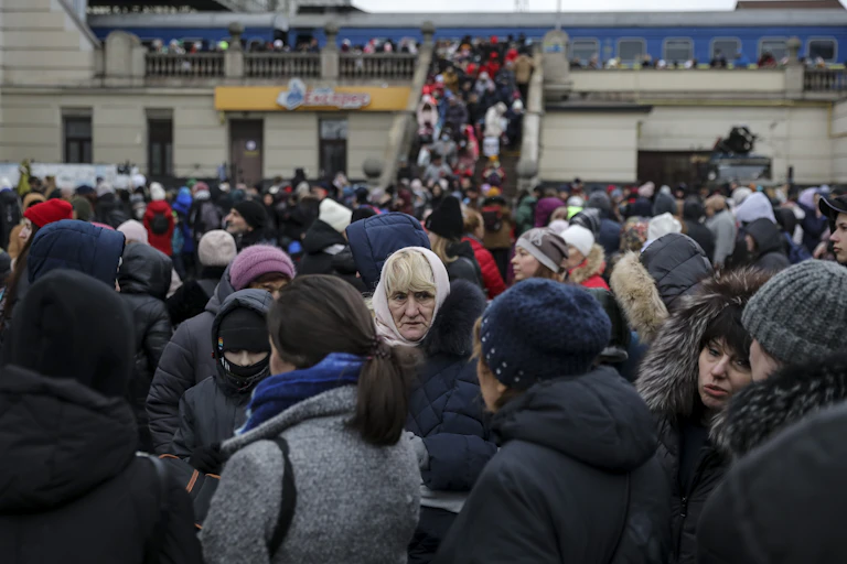 A large crowd of people gathering at a train station in Ukraine, try to board trains.
