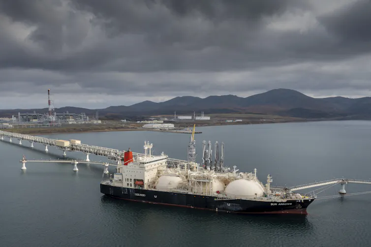 A ship sitting several hundreds of metres offshore connected to an industrial facility by a long pipeline.