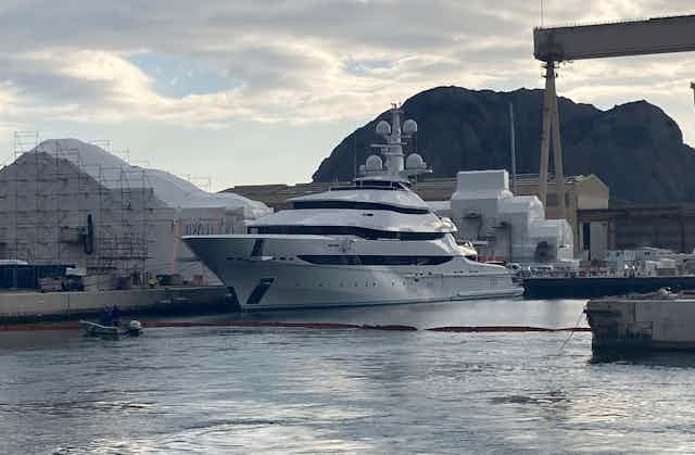 A large gleaming white yacht sits in a harbour.