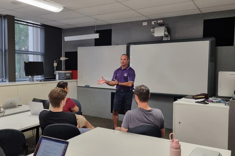 A person stands in front of a classroom, teaching.