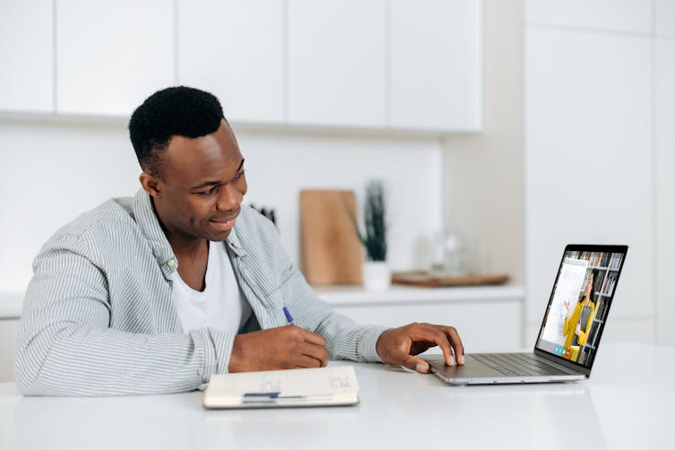 Student sitting in kitchen as he chats online with teacher