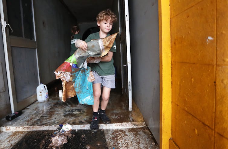 boy carries debris from house