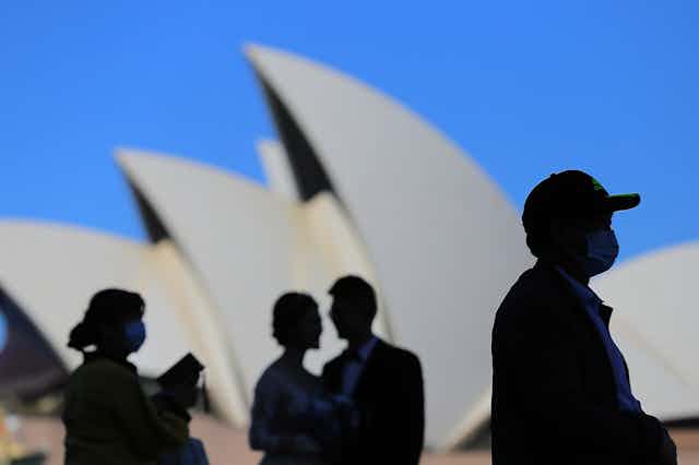 People wearing masks in front of the Sydney Opera House, March 2020