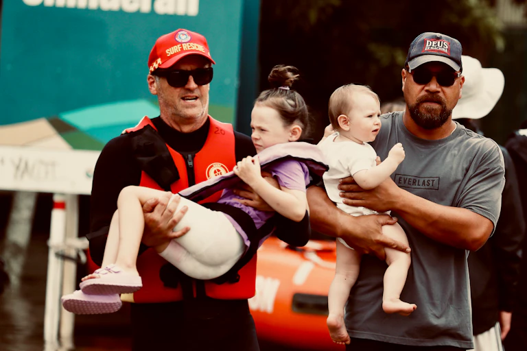 two men carry children