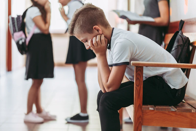 Young schoolboy sitting on bench with head in his hands