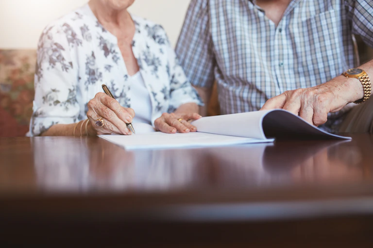 older couple signing documents